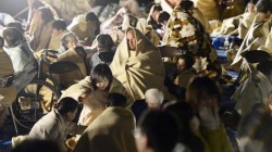 Local residents wrap themselves in blankets as they sit on the road in front of the town office building after an earthquake in Mashiki town, Kumamoto in april 2016