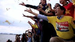 Protesters throws flowers while chanting anti-Chinese slogans during a rally by different activist groups over the South China Sea disputes, along a bay in metro Manila