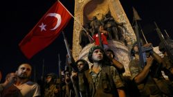 Turkish military stand guard near the the Taksim Square as people wave with Turkish flags in Istanbul, Turkey, July 16, 2016.