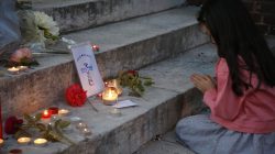 A young girl prays near flowers and candles at the city hall in Saint-Etienne-du-Rouvray to pay tribute to Father Jacques Hamel, who was killed in an attack on a church