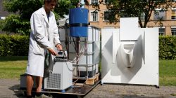 Belgian scientist Derese pours water from a machine that turns urine into drinkable water and fertilizer using solar energy, at the University of Ghent