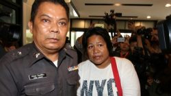 Patnaree Chankij, the mother of an anti-junta activist, is escorted by police as she arrives at a military court in Bangkok, Thailand