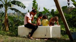 Lisibeht Martinez (L), 30, who was sterilized one year ago, sits next to her children while they play in a bathtub in the backyard of their house