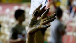 A drug user raises his ink smeared hand after he surrendered to local government officials to take part in a government