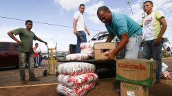 Men load boxes of food onto the back of a pick-up truck, after arriving from Brazil, in front of the bus terminal in Santa Elena de Uairen