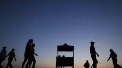 People walk and exercise by a lake in Yangon at sunrise
