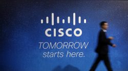 person walking past Cisco logo