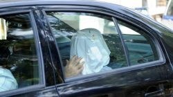 One of the eight Turkish soldiers, who fled to Greece in a helicopter and requested political asylum after a failed military coup against the government, is seen in a police car with his face covered.