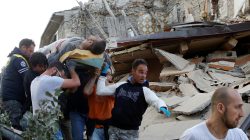 A man is carried away after having been rescued alive from the ruins following an earthquake in Amatrice