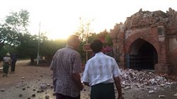 Two men look at a collapsed entrance of a pagoda after an earthquake in Bagan