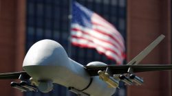 A model of a military drone is seen in front of an U.S. flag as protesters rally against climate change, ahead of the Democratic National Convention, in Philadelphia
