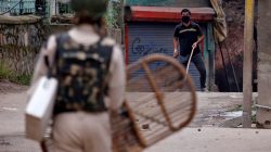 A protester prepares to throw a stone towards an Indian policeman during a protest in Srinagar against the recent killings in Kashmir