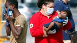 A Red Cross member carries a child as migrants disembark from the Italian Navy vessel Sfinge in the Sicilian harbour of Pozzallo, southern Italy