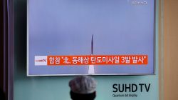 A passenger watches a TV screen broadcasting a news report on North Korea firing three ballistic missiles into the sea off its east coast, at a railway station in Seoul, South Korea,