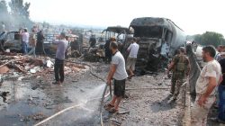 Syrian army soldiers and civilians inspect the site of two explosions that hit the Arzouna bridge area at the entrance to Tartous