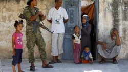 A member of Turkish-backed Free Syrian Army (FSA) is seen with local people in the border town of Jarablus, Syria,