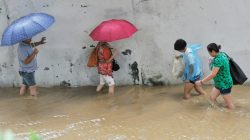 People wading through flooded street after Typhoon Meranti