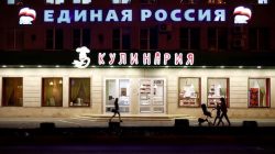 People walk past a sign reading "United Russia" on a building in central Stavropol, Russia,