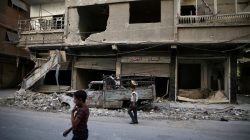 Children walk near damaged buildings in rebel-held Ain Tarma, eastern Damascus suburb of Ghouta, Syria September 17, 2016