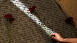 A man lays a flower on a monument engraved with names of victims of the September 11th attacks, during a memorial event marking the 15th anniversary