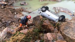 A rescue worker is seen next to an overturned car at the site of a landslide caused by heavy rains brought by Typhoon Megi, in Sucun Village, Lishui
