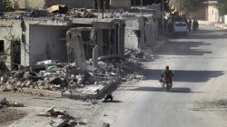 A rebel fighter rides past damaged buildings in al-Rai town, northern Aleppo countryside,
