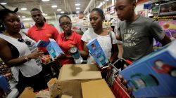 A saleswoman shows lamps to a customers while other people flock to the supermarket to take care of last minute shopping as Hurricane Matthew approaches in Kingston, Jamaica