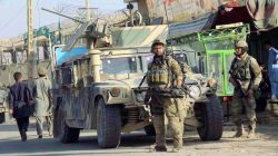 Afghan security forces keep watch in front of their armoured vehicle in Kunduz city, Afghanistan