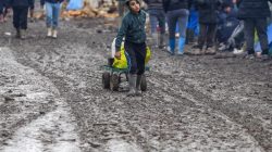 A young migrant pulls a trolley in a muddy field at a camp of makeshift shelters for migrants and asylum-seekers from Iraq, Kurdistan, Iran and Syria, called the Grande Synthe jungle, near Calais, France,