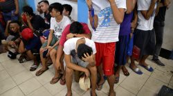 People wait to be processed at a police station, after they were detained in a police "One Time Bigtime" operation against illegal drugs in metro Manila,