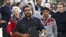 UK Border Force staff escort the first group of unaccompanied minors from the Jungle migrant camp in Calais to be brought to Britain as they arrive at an immigration centre in Croydon, south London,