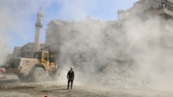 A Civil Defence member stands as a front loader removes debris after an air strike Sunday in the rebel-held besieged al-Qaterji neighbourhood of Aleppo