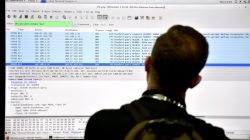 An attendee looks at a monitor at the Parsons booth during the 2016 Black Hat cyber-security conference in Las Vegas, Nevada, U.S