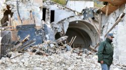An officer of the State Forestry Corp national police stands in front of a collapsed church in Campi di Norcia, central Italy
