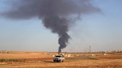 Rebel fighters ride a military vehicle near rising smoke from al-Bab city, northern Aleppo province, Syria