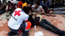 A Spanish Red Cross worker aids African migrants after they crossed a border fence between Morocco and Spain's north African enclave of Ceuta