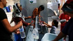 Anis, 4, from Syria (C) is bathed by his mother, as others wash their clothes and shoes, at the Souda municipality-run camp for refugees and migrants on the island of Chios, Greece
