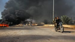 Rebel fighters drive their motorcycles under the smoke of burning tyres, western Aleppo city,