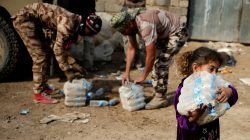Little girl carrying bottled water in Iraqi village