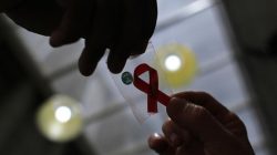 A nurse (L) hands out a red ribbon to a woman, to mark World Aids Day, at the entrance of Emilio Ribas Hospital, in Sao Paulo