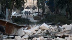 People walk near rubble of damaged buildings, in the rebel-held besieged area of Aleppo, Syria