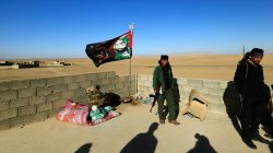 Shi'ite fighters stand with their weapons on the top of a building in Ali Rash, southeast of Mosul, Iraq