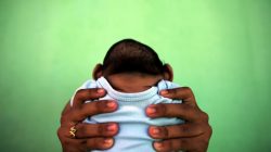 A 4-month-old baby born with microcephaly is held by his mother in front of their house in Olinda, near Recife, Brazil,