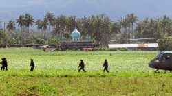 Soldiers walk across a field near a mosque after disembarking from a military helicopter in Butig, Lanao del Sur, southern Philippines