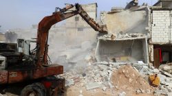 excavator removing rubble after air strikes