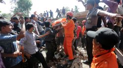 Rescue workers and police remove a victim from a collapsed building following an earthquake in Lueng Putu, Pidie Jaya in the northern province of Aceh, Indonesia
