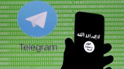 A man holds a smartphone showing the Islamic State logo in front of a screen showing the Telegram logo in this picture illustration taken in Zenica, Bosnia and Herzegovina
