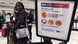 A woman looks at a Center for Disease Control (CDC) health advisory sign about the dangers of the Zika virus as she lines up for a security screening at Miami International Airport in Miami, Florida,