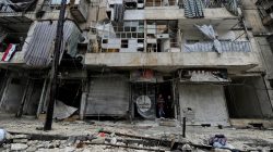 Boys stand amid the damage in the government-held al-Shaar neighborhood of Aleppo, during a media tour, Syria