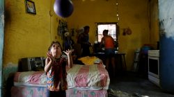 Emmanuel Cuauro, 4, plays with a ball next to his parents Zulay Pulgar (R), 43, and Maikel Cuauro, 30, in their house in Punto Fijo, Venezuela